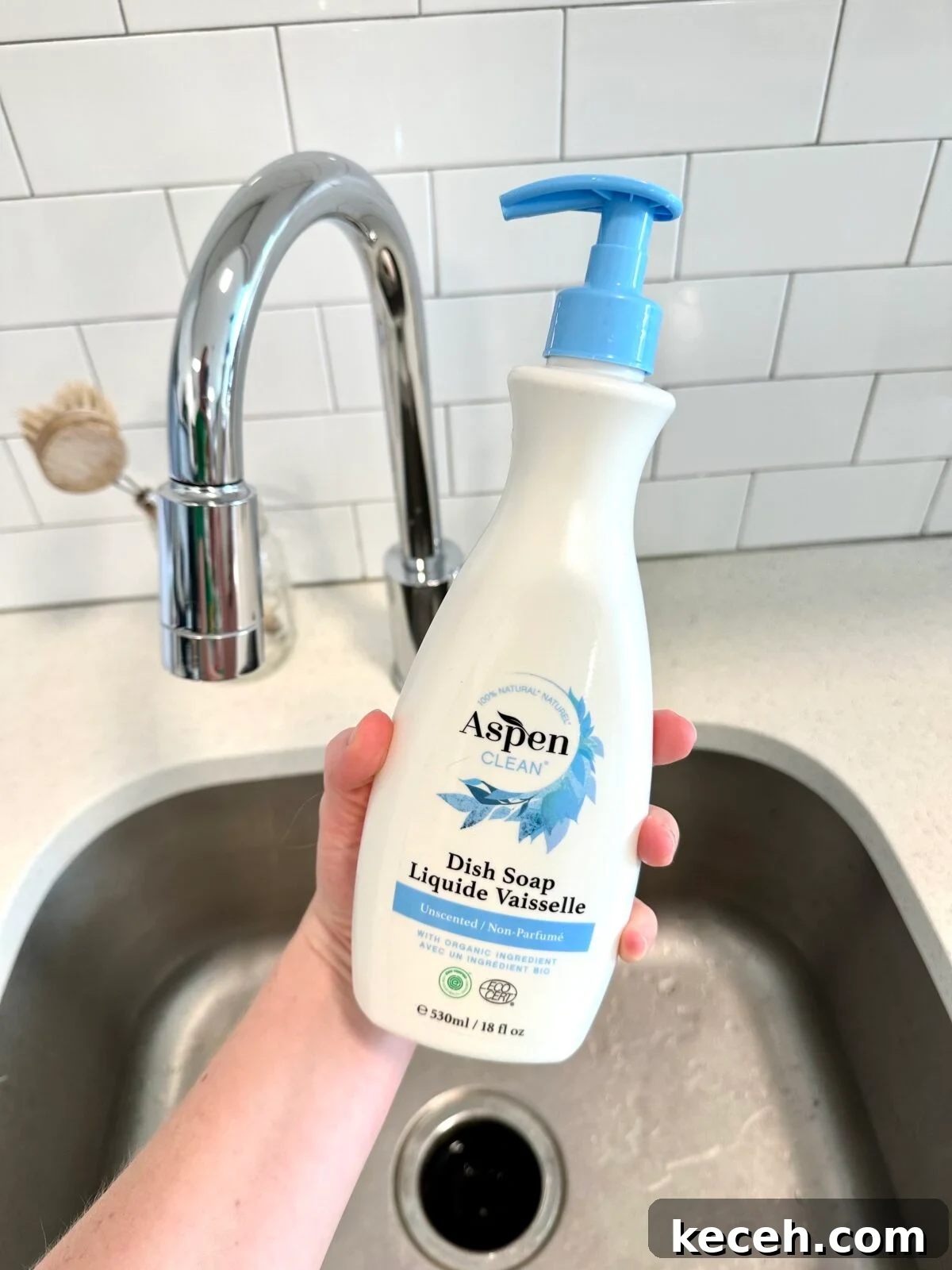 a person holding a natural dish soap in front of the sink from AspenClean 