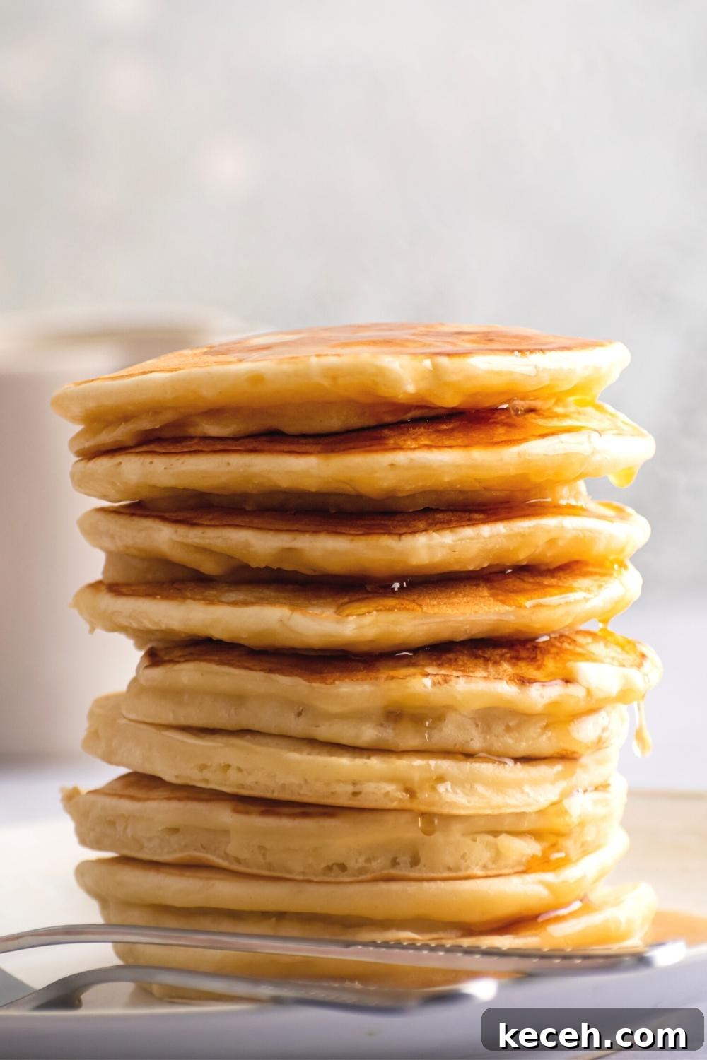A stack of a bunch of pancakes with maple syrup dripping down the sides of them.