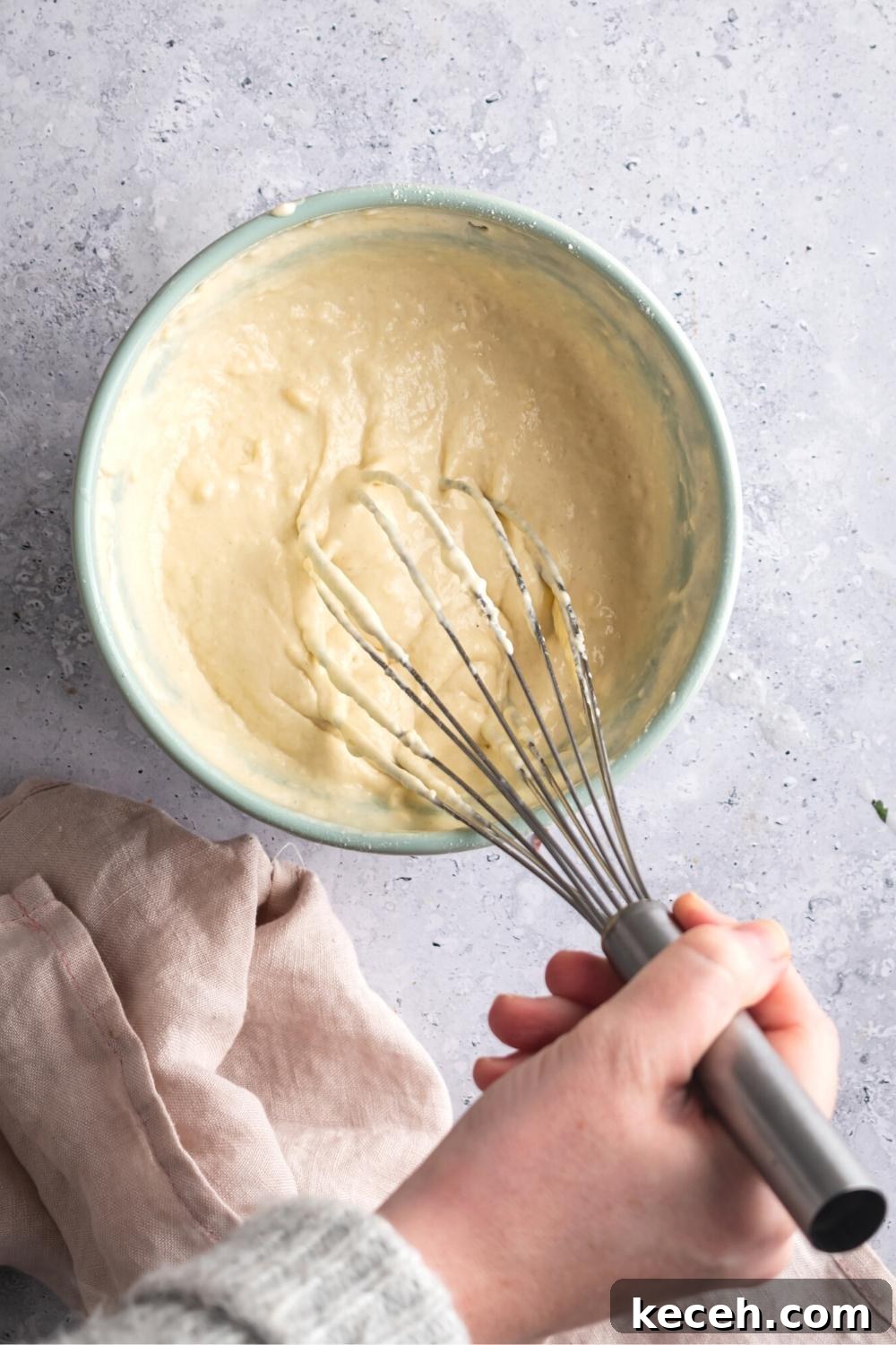 A hand whisking together Denny's pancake ingredients.