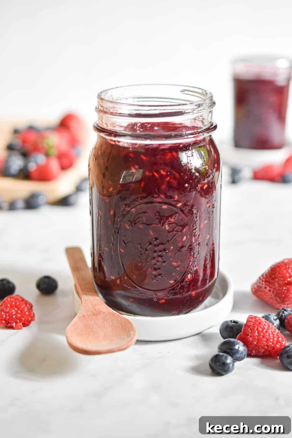 A close up of the instant pot mixed berry jam surrounded by fruit.