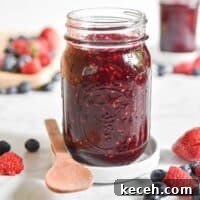 A close up of the instant pot mixed berry jam surrounded by fruit.