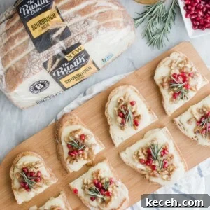 Pomegranate, Brie & Walnut Crostini Recipe for Holiday Entertaining 10 Slices of sourdough bread topped with cheese, pomegranate seeds, walnuts, and rosemary are arranged on a wooden board. Nearby, a package of sourdough bread, a bowl of honey, and more pomegranate seeds are visible.