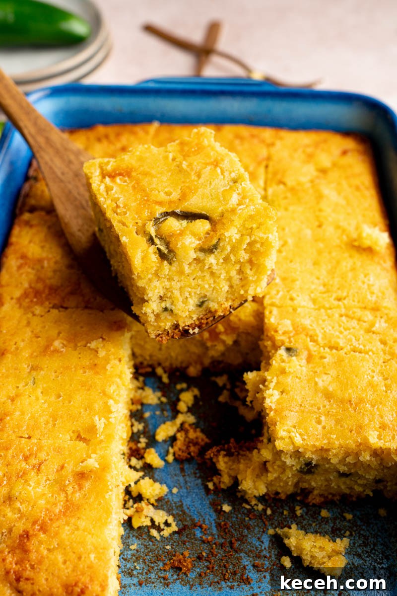 Spicy Jalapeño Cheddar Cornbread Recipe 6 A serving utensil picks up a piece of the jalapeno cheddar cornbread from the baking dish for serving.