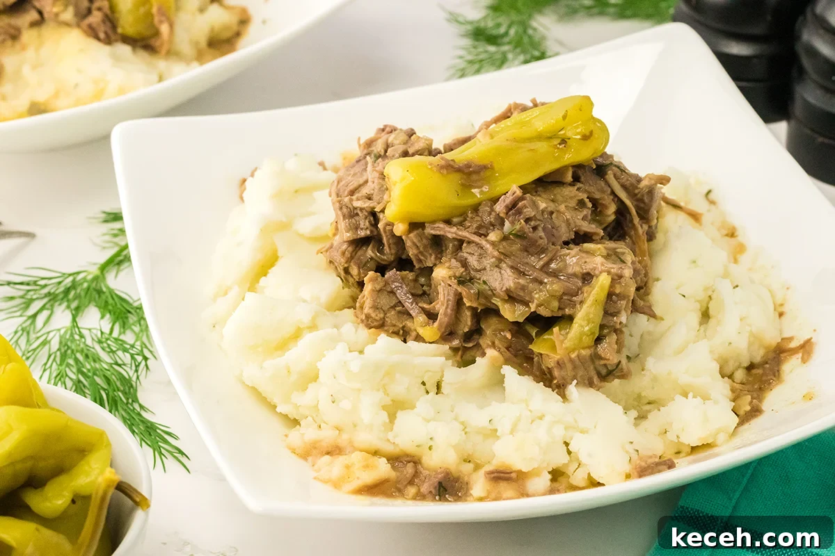 Mississippi Pot Roast on white plate on top of Mashed Potatoes.