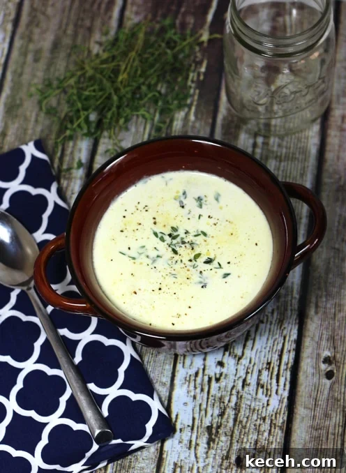 Creamy Truffled Cauliflower Soup Recipe for Gourmet Flavor 2 A bowl of truffled cauliflower soup on a wooden table with a spoon on the side.