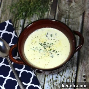 A bowl of truffled cauliflower soup on a wooden table with a spoon on the side.