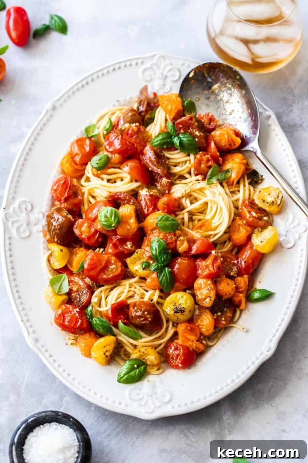 Roasted Cherry Tomato Pasta with Garlic and Basil 2 large white platter of pasta, topped with roasted tomato sauce and garnished with basil leaves. silver spoon on edge of dish.