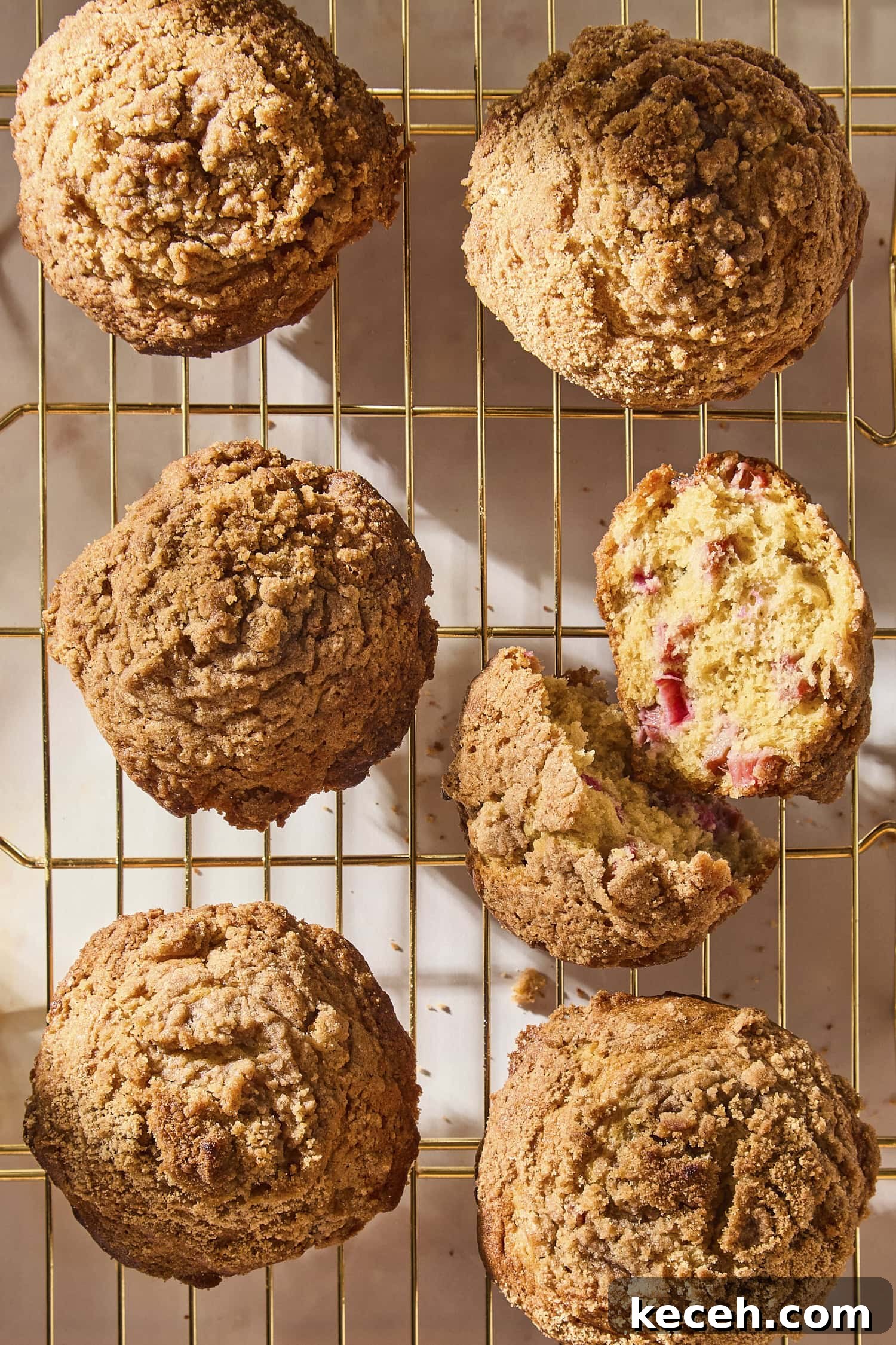Tangy Rhubarb Muffins with Crunchy Streusel Topping 3 Wire cooling rack with rhubarb muffins after baking with one broken in half.