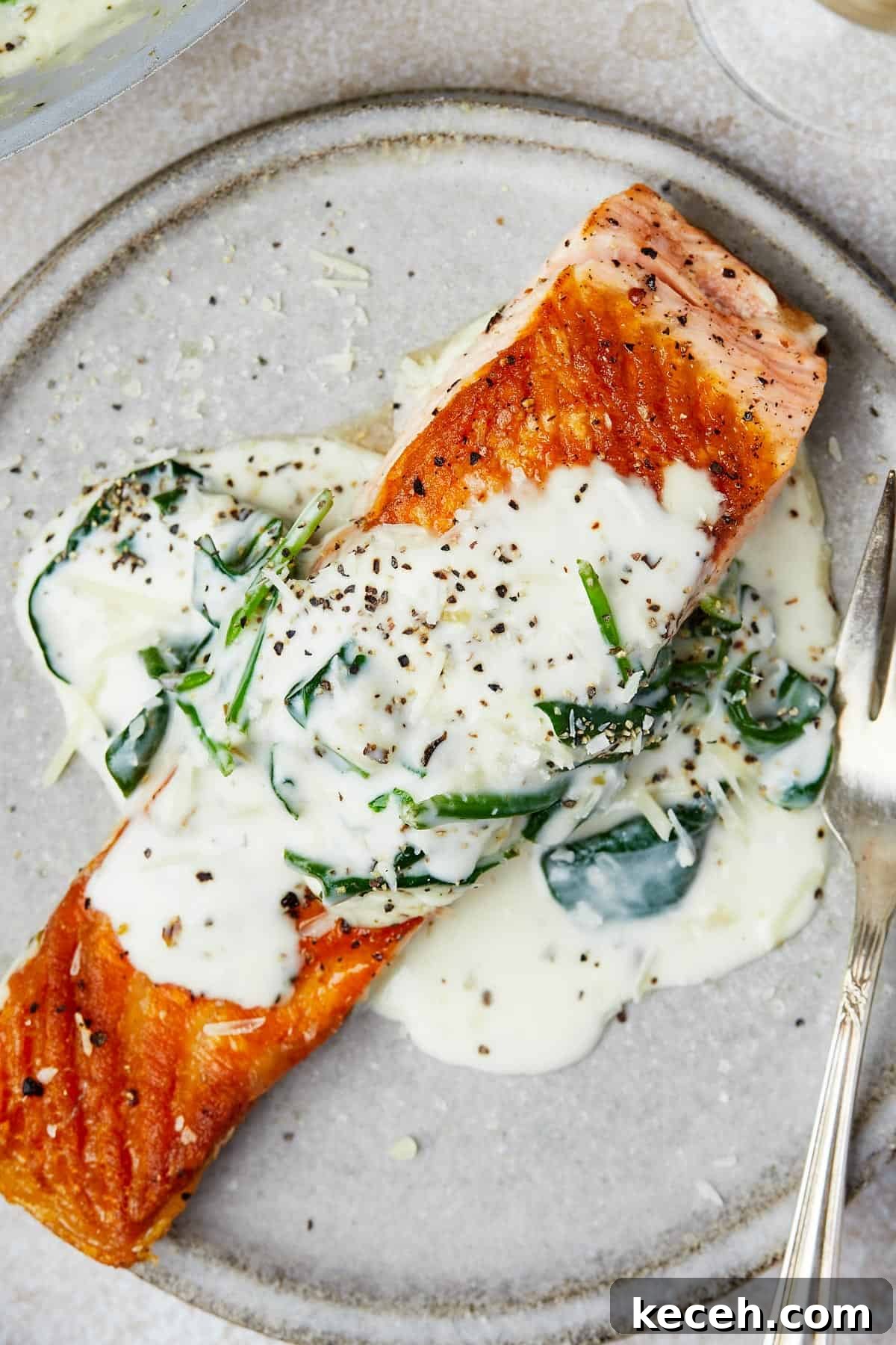 Creamy Spinach Salmon Florentine Recipe for Weeknight Dinners 10 A salmon fillet topped with creamy sauce on a small plate.