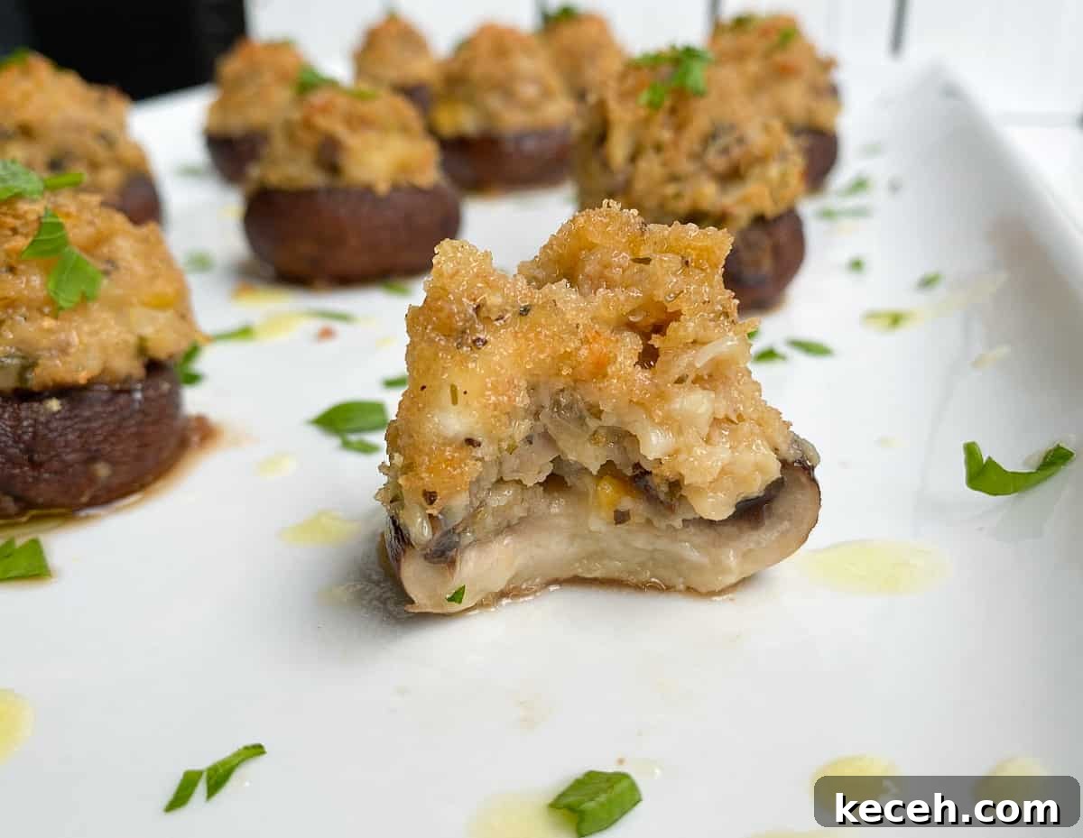 Olive Garden Clam-Stuffed Mushrooms Recipe: Copycat Appetizer 7 A bite taken out of an Italian stuffed mushroom on a plate.