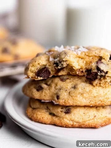 A stack of 3 sourdough chocolate chip cookies with milk in the back.