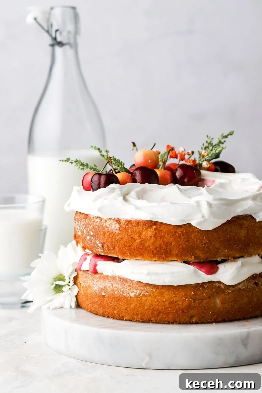 white forest cake with fresh cherries and flowers on top