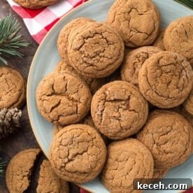 Several Soft Chewy Ginger Cookies on grey plate with red gingham napkin and pine needles in background