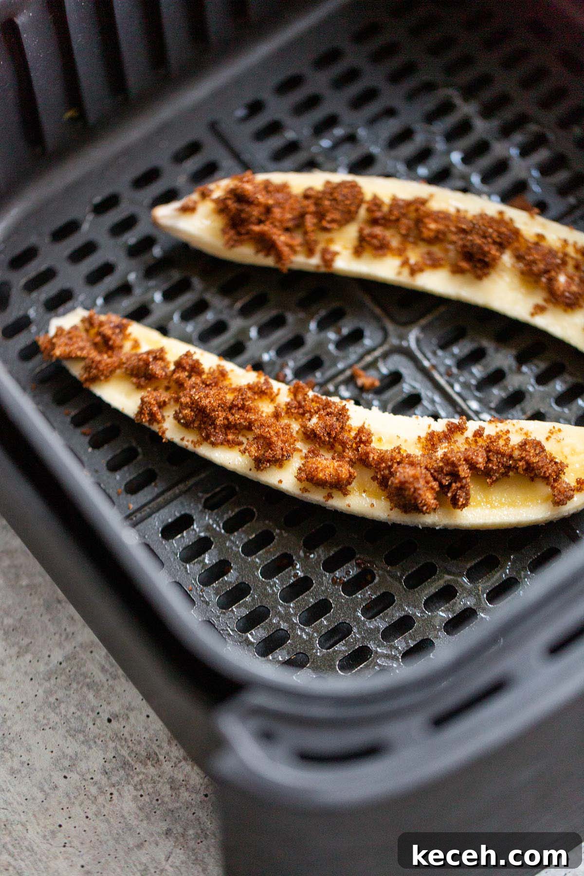 Air Fryer Banana Split Dessert with Warm Caramel and Crisp Toppings 5 Banana topped with brown sugar mixture in air fryer basket.
