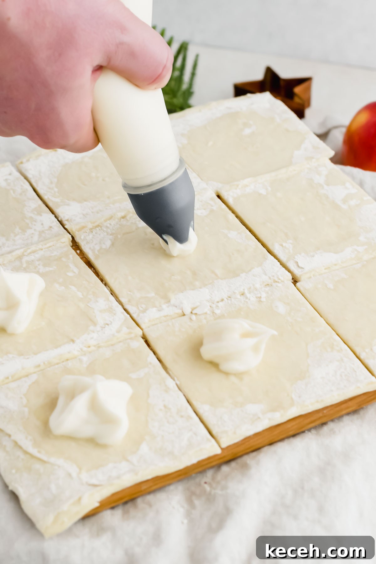 prozen puff pastry cut into squares and being filled with cream cheese.