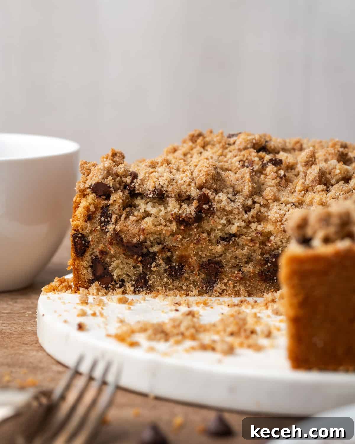 A sliced chocolate chip coffee cake sitting on a white cutting board.