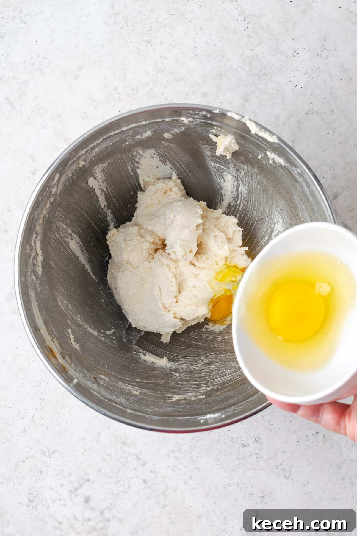 Eggs being added one at a time to the partially mixed coffee cake batter.