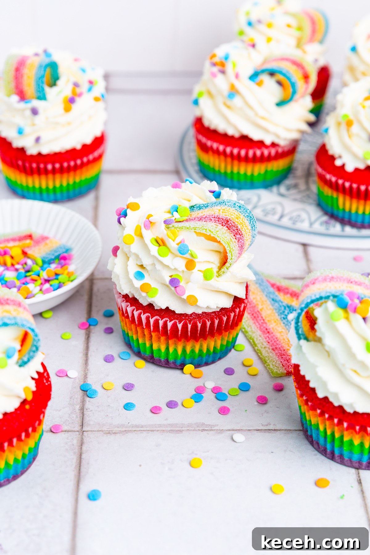 How to Make Colorful Rainbow Cupcakes at Home 2 rainbow cupcakes on a table with colorful layered sponge and mascarpone frosting