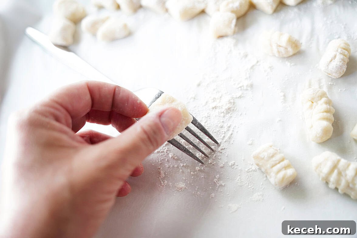 Pillowy Homemade Potato Gnocchi: Classic Italian Comfort Food 9 hand holding fork rolling potato gnocchi to make ridges to help hold sauce