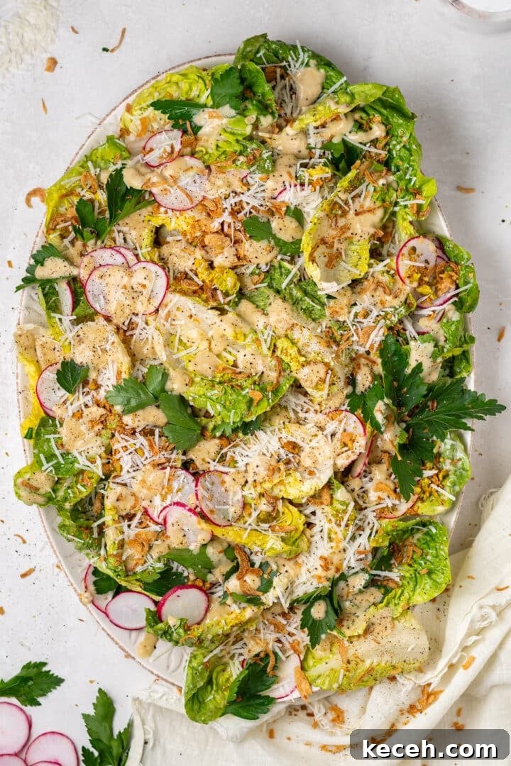 little gem salad recipe with Caesar vinaigrette, parmesan cheese, pistachios, and crispy shallots on platter