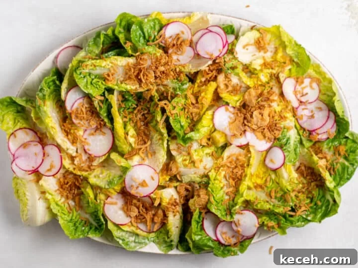 little gem salad topped with radishes and crispy shallots before adding remaining caesar vinaigrette 