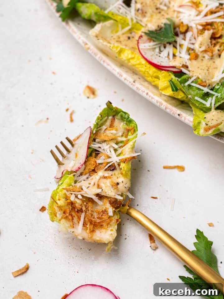 little gem salad bite with Caesar vinaigrette, crispy shallots, parmesan, and radish on fork