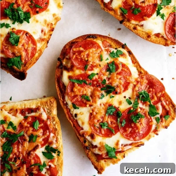 Four slices of pepperoni French bread pizza topped with melted cheese and chopped parsley on a white surface.