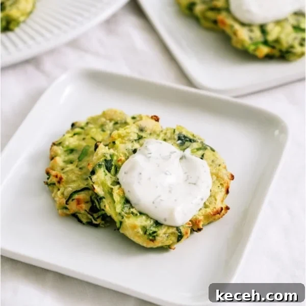 Crispy Air Fryer Zucchini Fritters on a plate topped with dill sour cream dip.