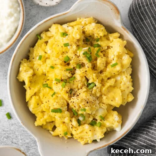 Scrambled eggs in a bowl with chives and sour cream.