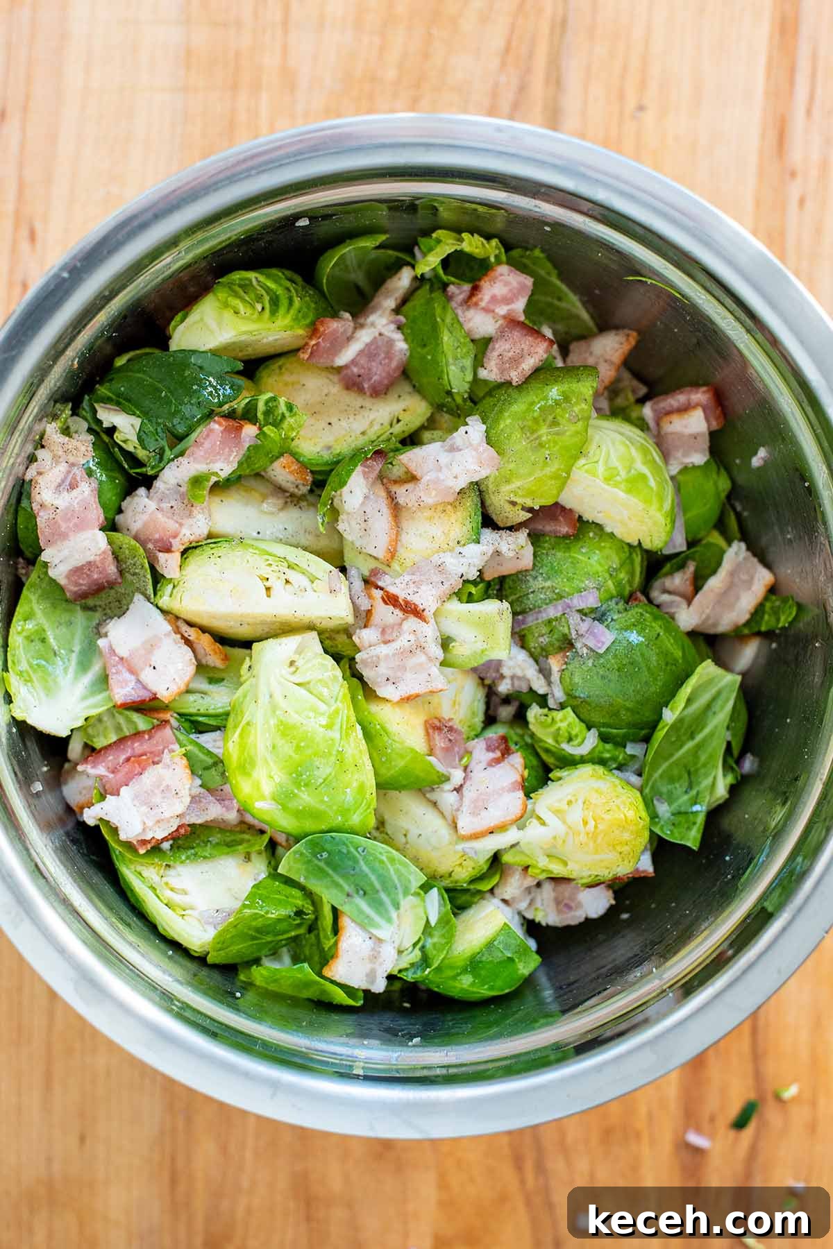 Crispy Roasted Brussels Sprouts with Bacon and Balsamic Glaze 6 Uncooked Brussels sprouts, chopped shallots, and chopped bacon in a stainless steel bowl.