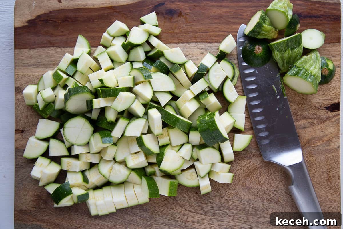 chopped zucchini and a knife on a wooden cutting board.