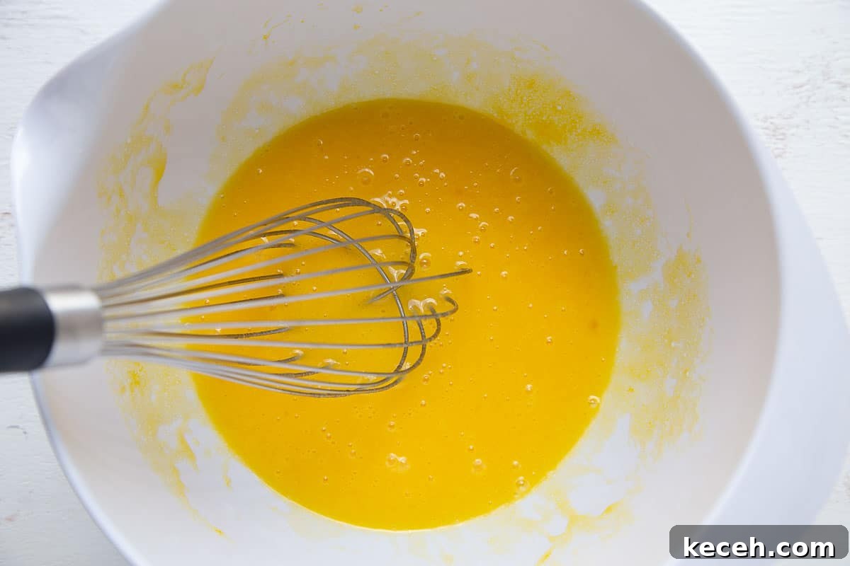 egg mixture in a white bowl with a whisk.