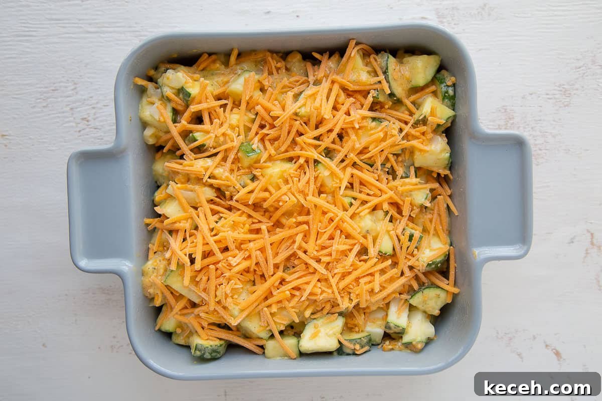 casserole dish filled with raw zucchini and topped with shredded cheddar.