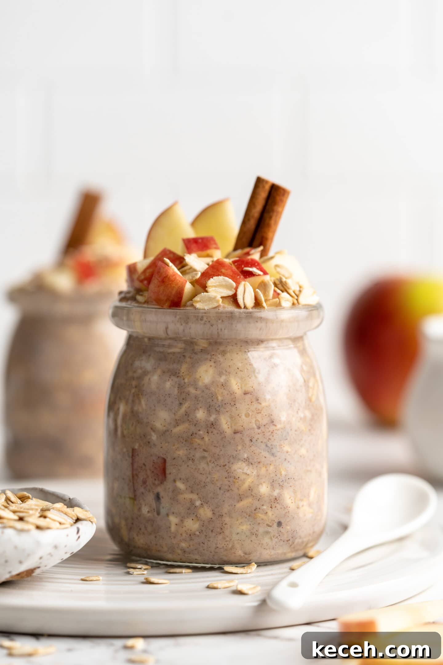 Apple pie overnight oats are packed with crisp apples, warm cinnamon, rich almond milk, and decadent maple syrup, and are an easy breakfast. two jars apple overnight oats with cinnamon sticks, oats and apples topping them