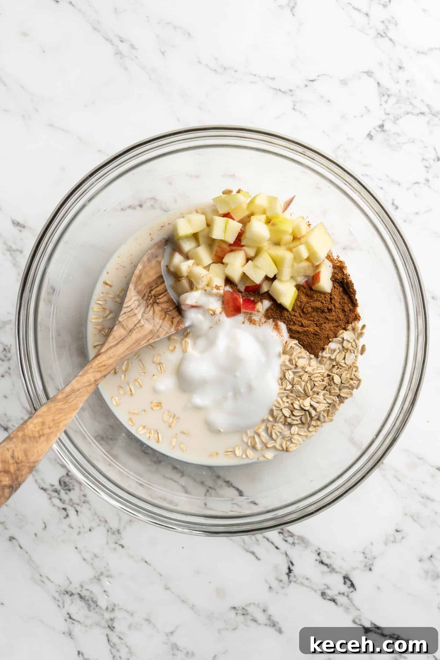 Apple Pie Overnight Oats Recipe for Cozy Fall M mornings 2 bowl of ingredients for overnight oats not yet mixed together with a wooden spoon