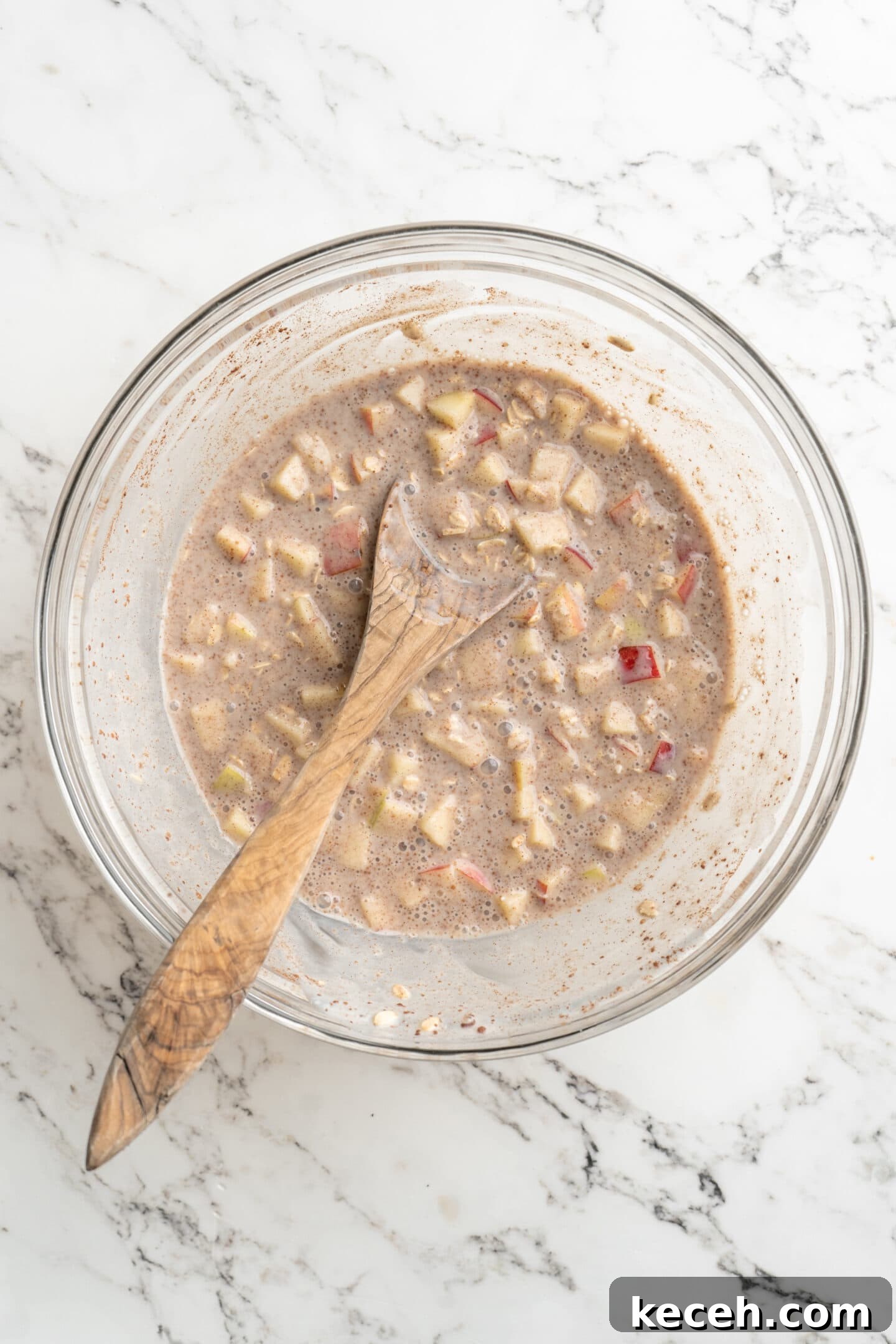 Apple Pie Overnight Oats Recipe for Cozy Fall M mornings 3 bowl of ingredients for overnight oats mixed together with a wooden spoon