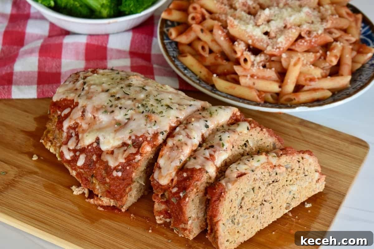 Italian-Style Turkey Meatloaf with Herbs and Parmesan 3 Sliced Italian turkey meatloaf on a cutting board with pasta.