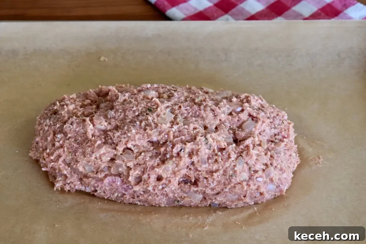 Italian-Style Turkey Meatloaf with Herbs and Parmesan 6 Italian turkey meatloaf shaped into a loaf on a piece of parchment paper.
