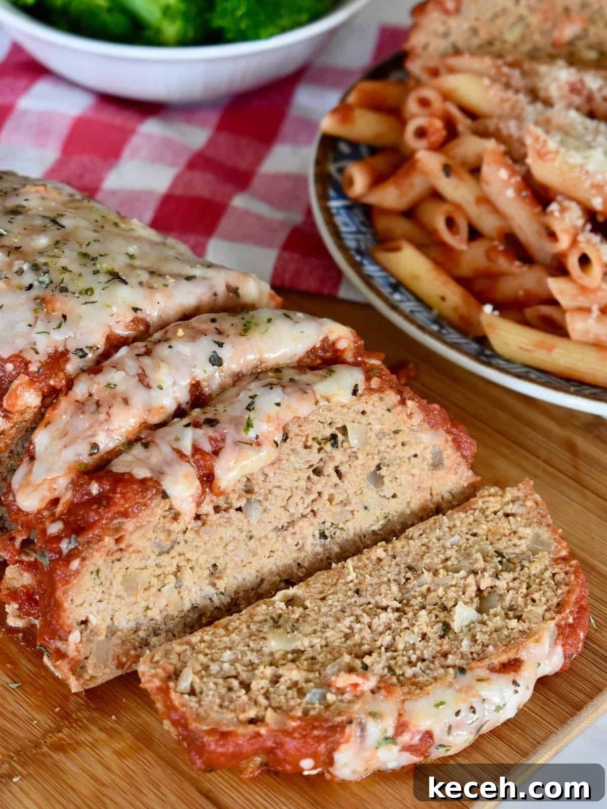 Italian-Style Turkey Meatloaf with Herbs and Parmesan 8 Sliced Italian turkey meatloaf on a cutting board with pasta next to it.