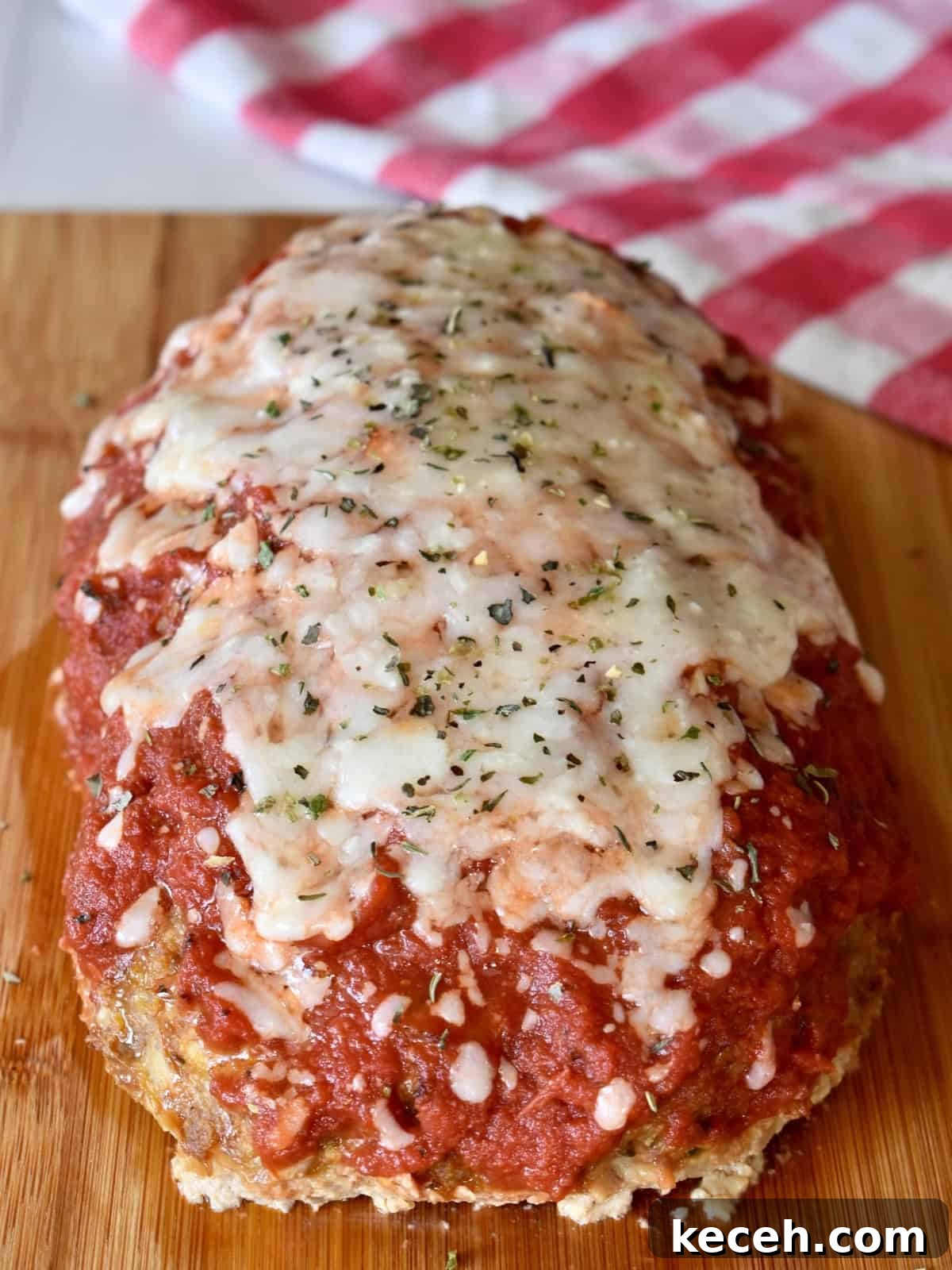Italian-Style Turkey Meatloaf with Herbs and Parmesan 9 Italian turkey meatloaf with marinara and cheese on top on a cutting board.