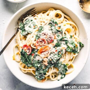 Family Meal Plan: Budget-Friendly Weekly Menu (Plan 138) 3 Creamy kale pasta with pine nuts and tomatoes in a white bowl.