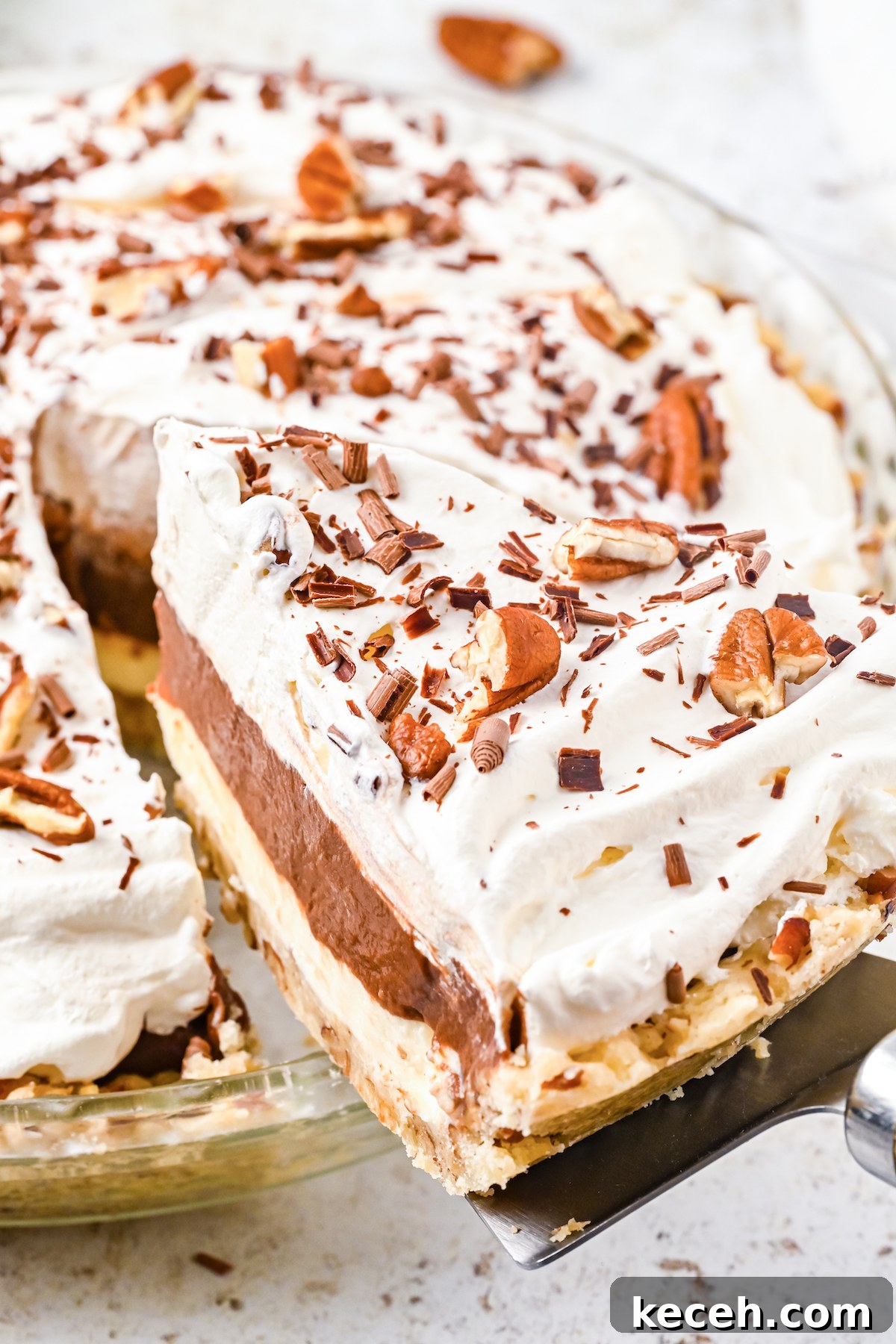 Southern Possum Pie Recipe: Classic Layered Chocolate Pudding Pie 3 A slice of possum pie been lifted out of a glass pie plate via a pie cutter.