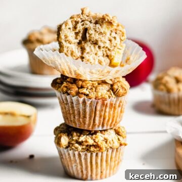 Stack of three apple crumble muffins. The top has a bite removed.