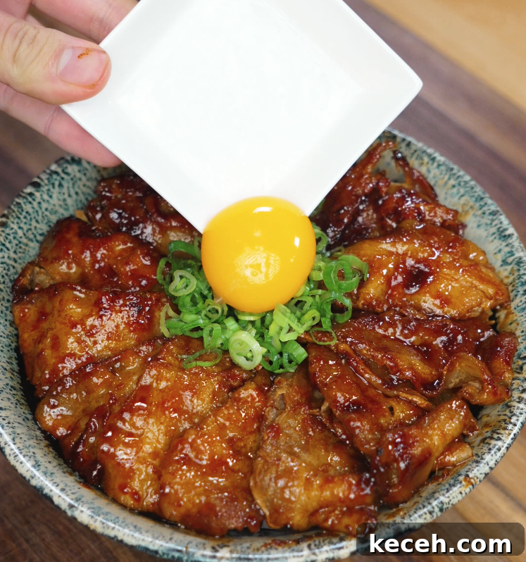 Sticky Spicy Pork Belly Recipe for Crispy Glazed Pork 7 Carefully placing a raw egg yolk on top of chopped green onions and sticky spicy pork belly slices arranged in a rice bowl, highlighting the contrast in textures and vibrant colors.
