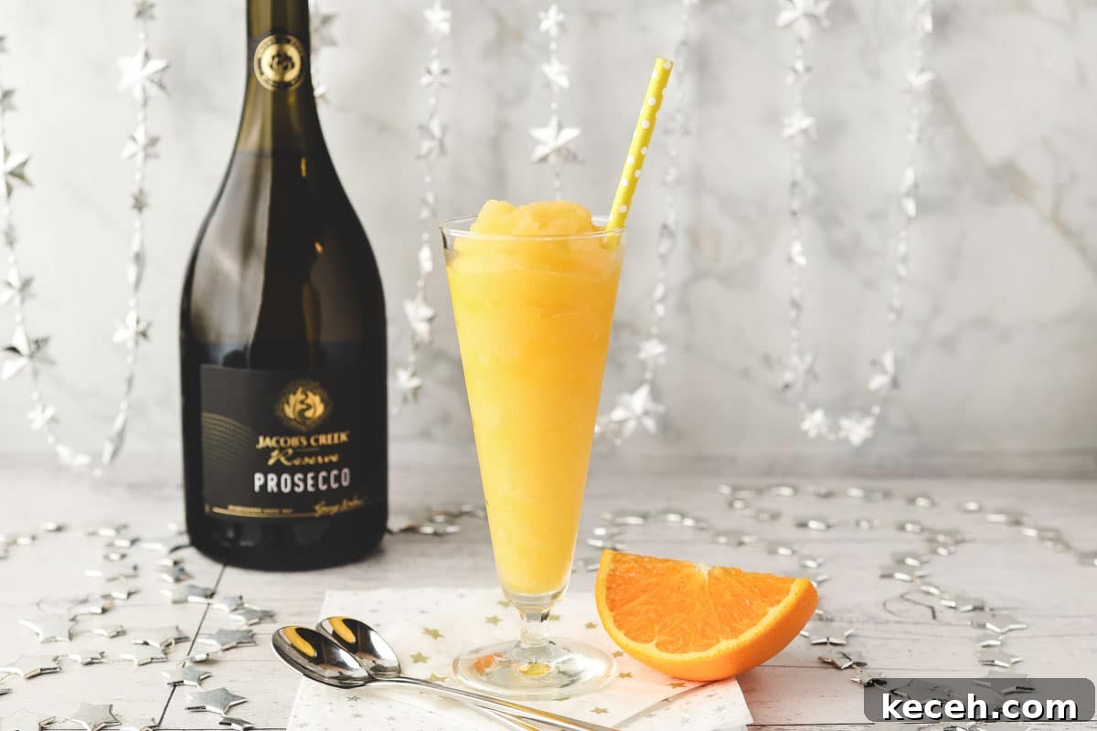 Mimosa Slushie Recipe: Sparkling Brunch Cocktail Guide 2 Glass of Mimosa slushy with tall spoons and fresh orange slice on the side.