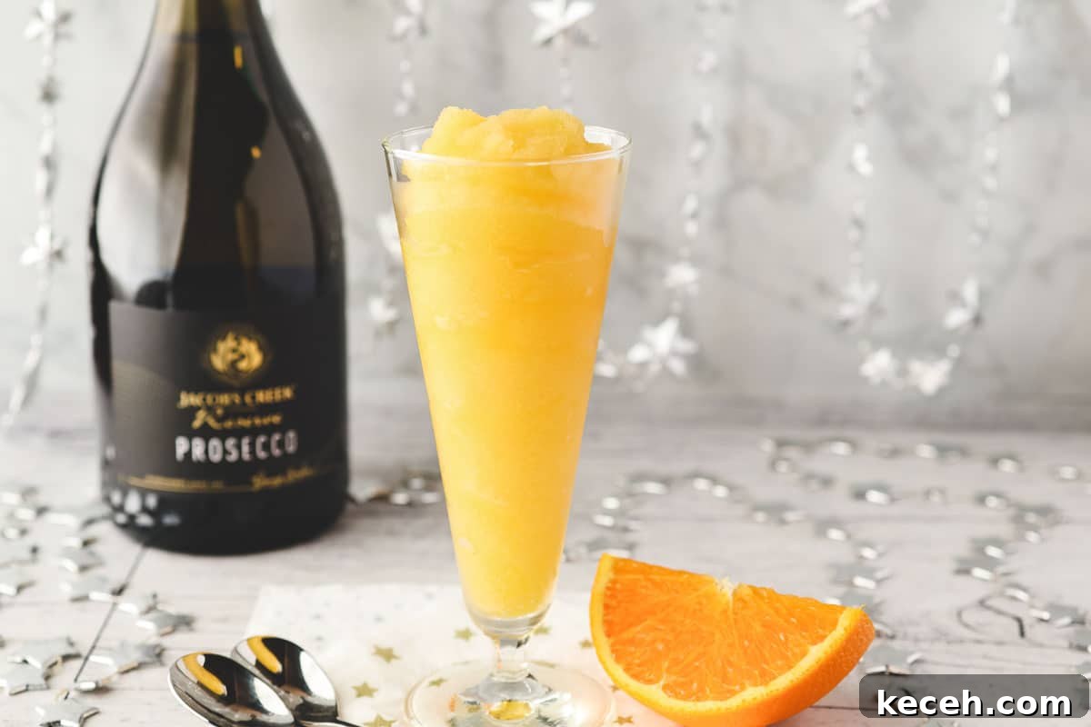 Mimosa Slushie Recipe: Sparkling Brunch Cocktail Guide 7 Glass of Mimosa slushy with tall spoons and fresh orange slice on the side.