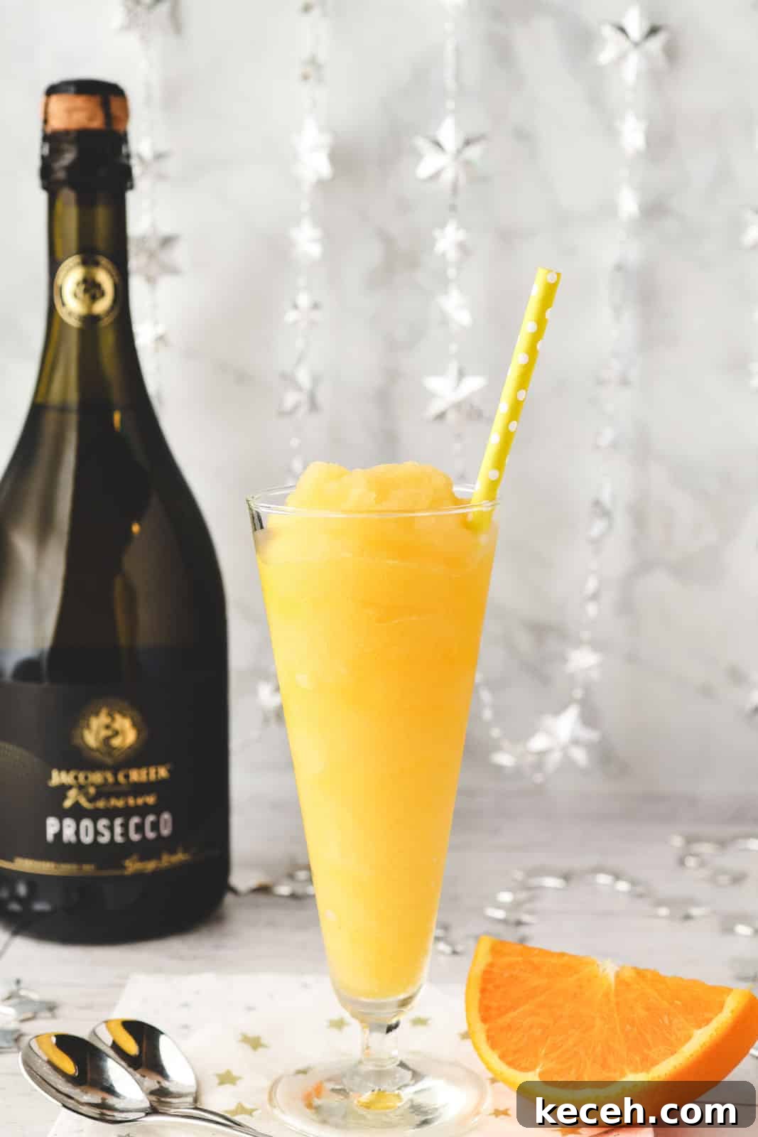 Mimosa Slushie Recipe: Sparkling Brunch Cocktail Guide 8 Glass of Mimosa slushy with tall spoons and fresh orange slice on the side.