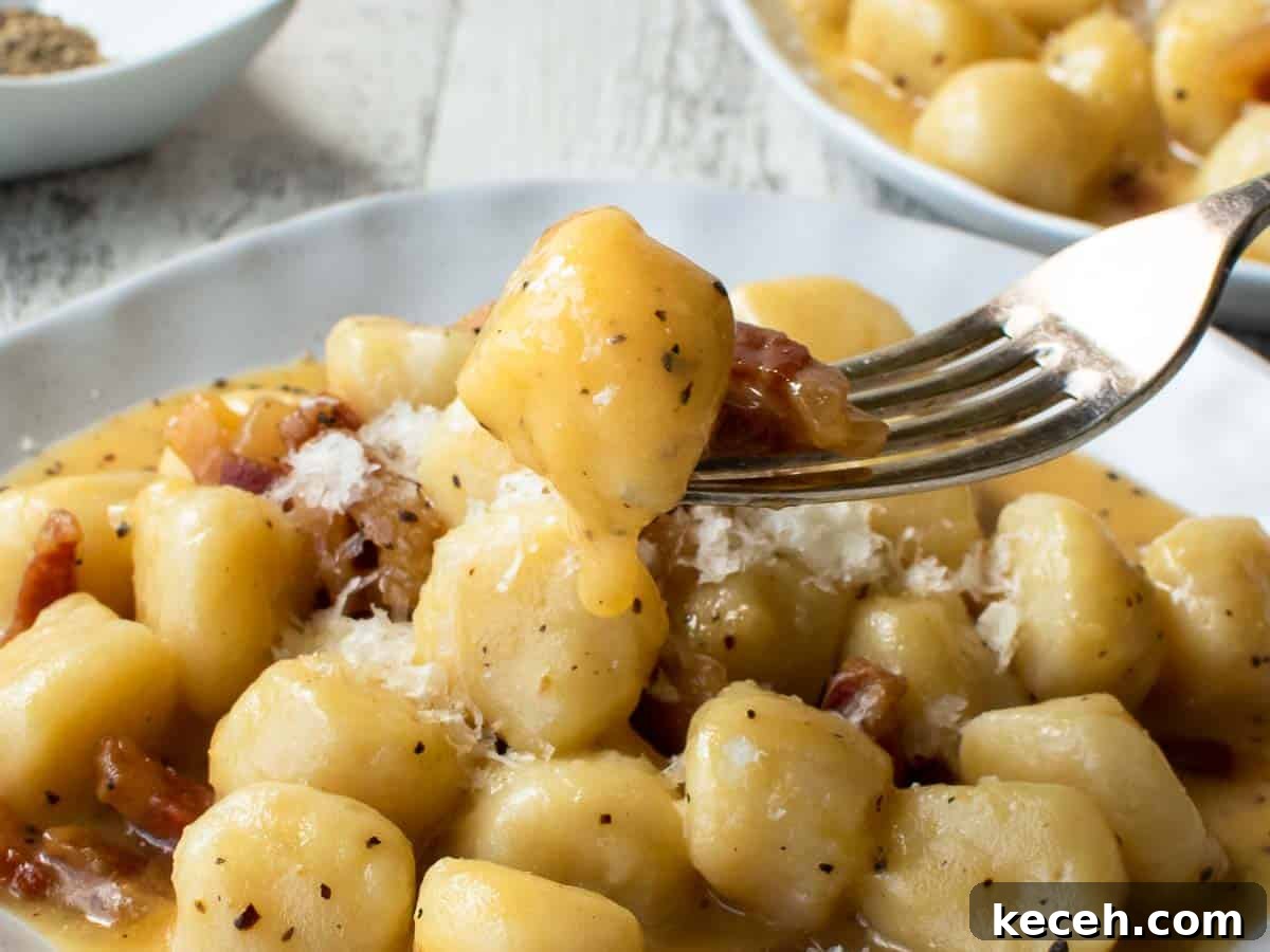 Close up of gnocchi on a fork with more in the background.