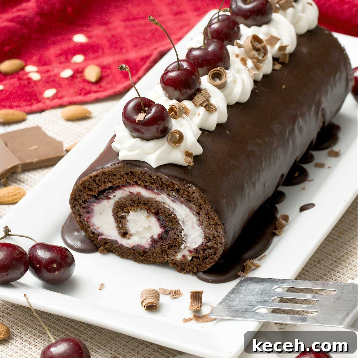 Gluten-Free Banana Cake with Chocolate Frosting Recipe 11 A gluten-free chocolate Swiss roll with cherries and whipped cream on top on a cake pan with a spatula.