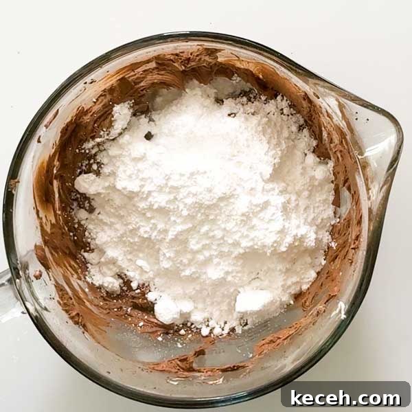 Gluten-Free Banana Cake with Chocolate Frosting Recipe 7 Adding powdered sugar to the bowl of chocolate frosting.